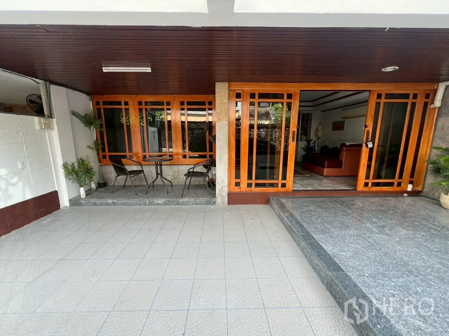Home Office for rent in Watthana, Bangkok - Front terrace with seating and steps leading to glazed wooden entrance.