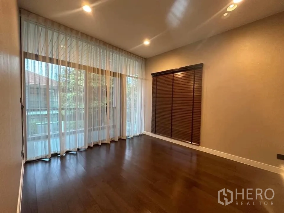 Detached House for rent in Bang Kapi, Bangkok - Spacious room with sheer curtains and timber blinds overlooking greenery.