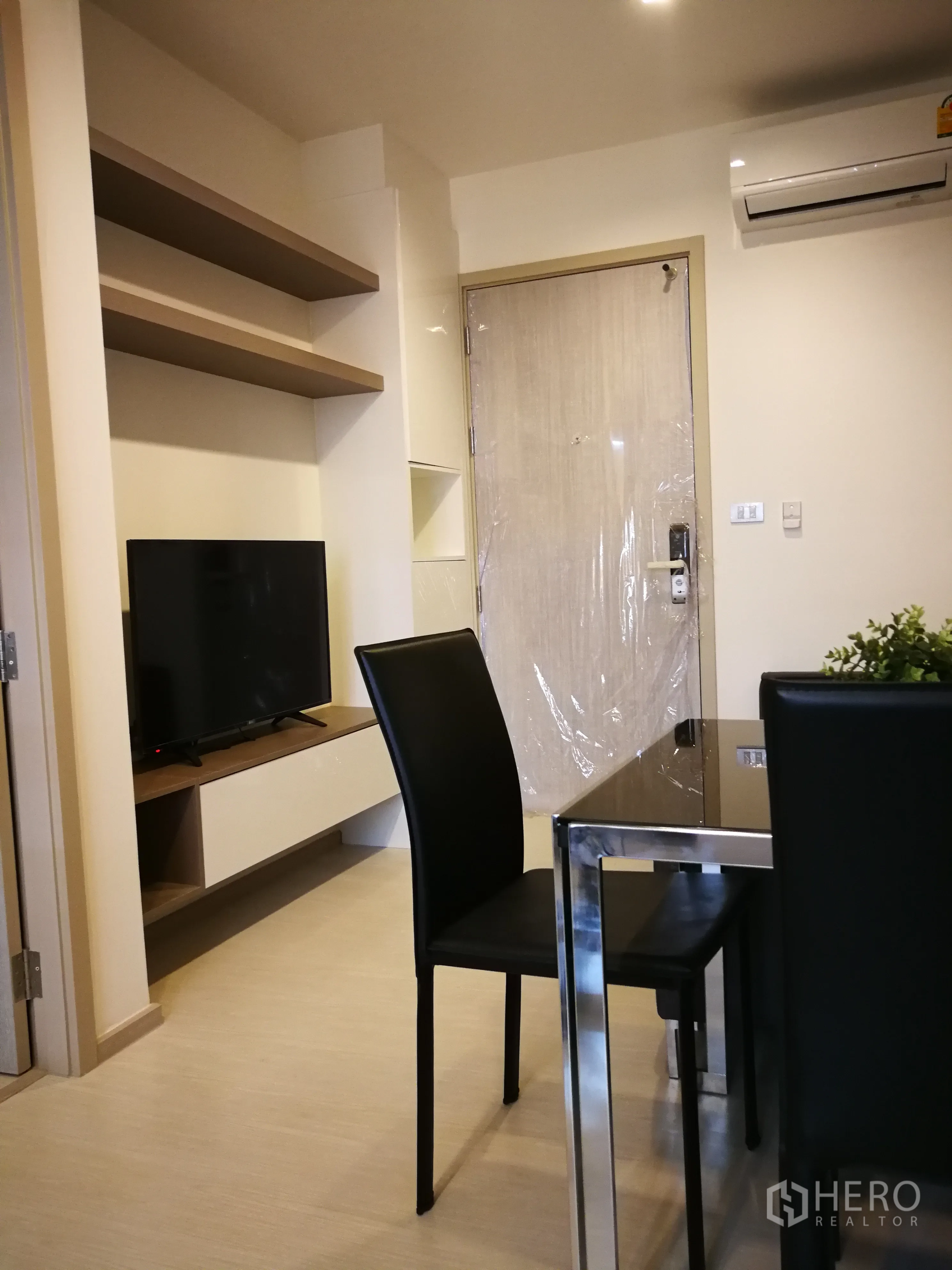 公寓 出租在Khlong Toei, Bangkok - 紧凑的客餐厅，带壁挂搁板、电视柜和空调。