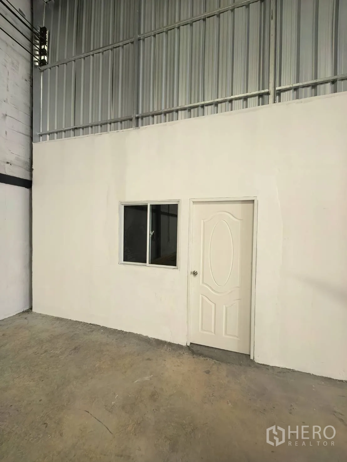 Warehouse for rent in Suan Luang, Bangkok - Internal office room inside the warehouse with a door and window set into the wall.