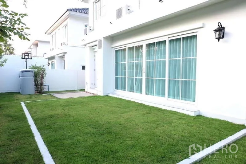 Detached House for rent in Bang Phli, Samut Prakan - Side garden with green grass and wide patio doors along the house.