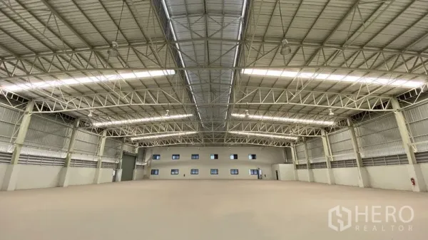 Factory for rent or sale in Samut Prakan - Spacious factory interior showing high clear‑span steel trusses and skylights.