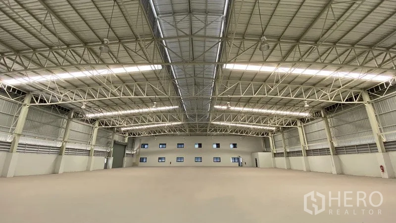 Factory for rent or sale in Samut Prakan - Spacious factory interior showing high clear‑span steel trusses and skylights.