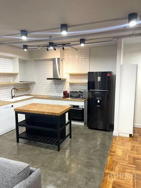 คอนโด ให้เช่าในWatthana, Bangkok - ครัวเปิดผนังกระเบื้องซับเวย์ เคาน์เตอร์ไม้ มีไอส์แลนด์และตู้เย็นสีดำ.