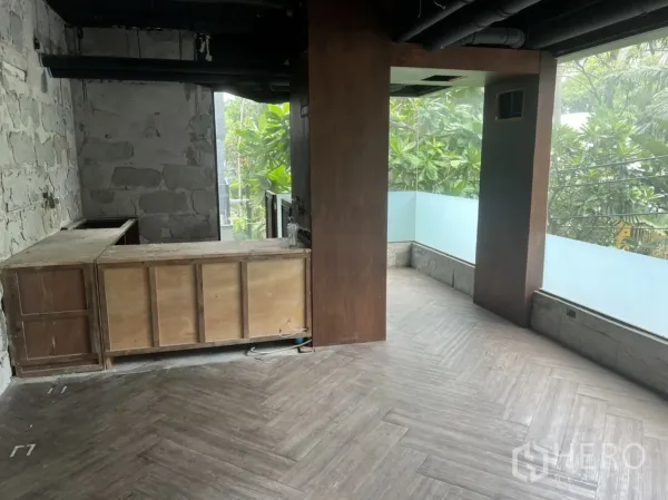 零售空间 出租在Khlong Toei, Bangkok - 角落空间带木质吧台、石墙与环绕落地玻璃窗，眺望绿植。