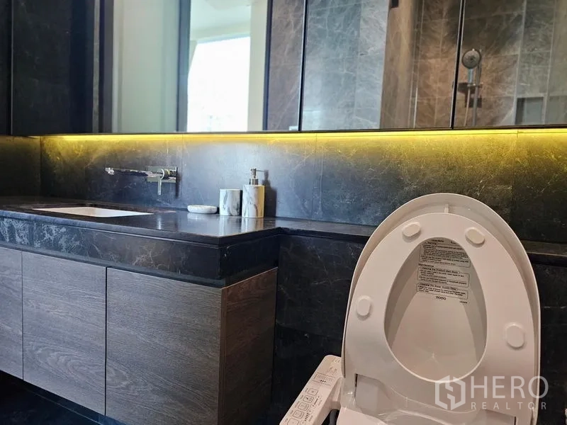 Condominium for rent - Close-up of bathroom vanity with backlit mirror and smart toilet.