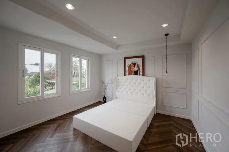 ทาวน์เฮาส์ ขาย - ห้องนอนมุมห้อง หน้าต่างสามบาน หัวเตียงบุนวมสีขาว และพื้นลายก้างปลา