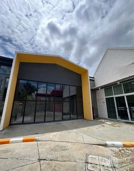 Retail Space for rent in Bang Na, Bangkok - Modern retail unit exterior with yellow-framed facade and large glass frontage on a wide driveway.