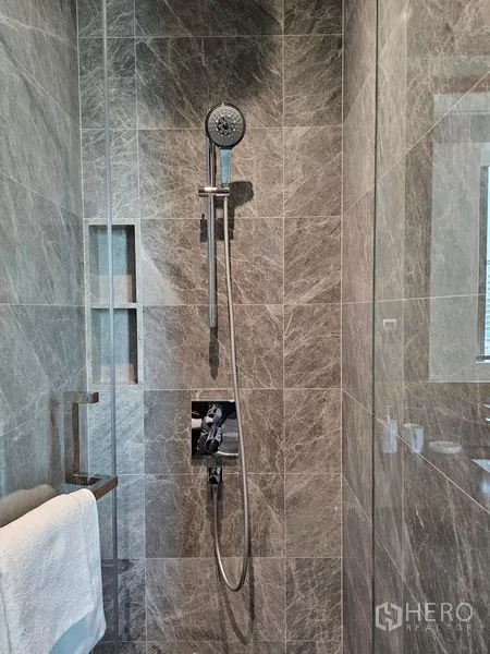 Condominium for rent - Walk-in shower featuring a handheld rain shower against marble tile walls.