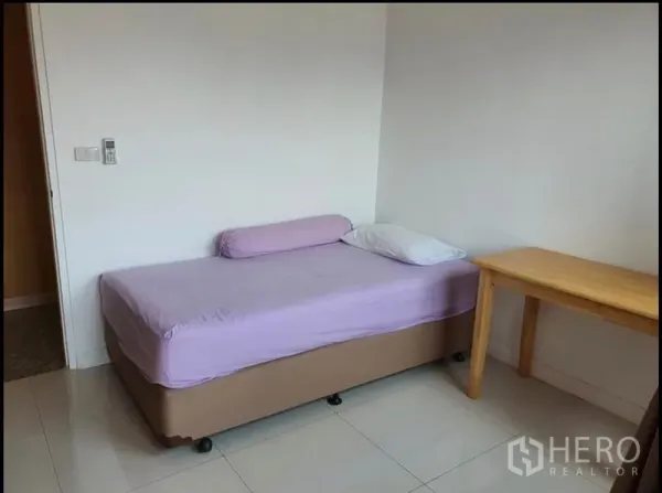 Condominium for rent in Ratchathewi, Bangkok - Bright bedroom with single bed, wooden side table and tiled floor.