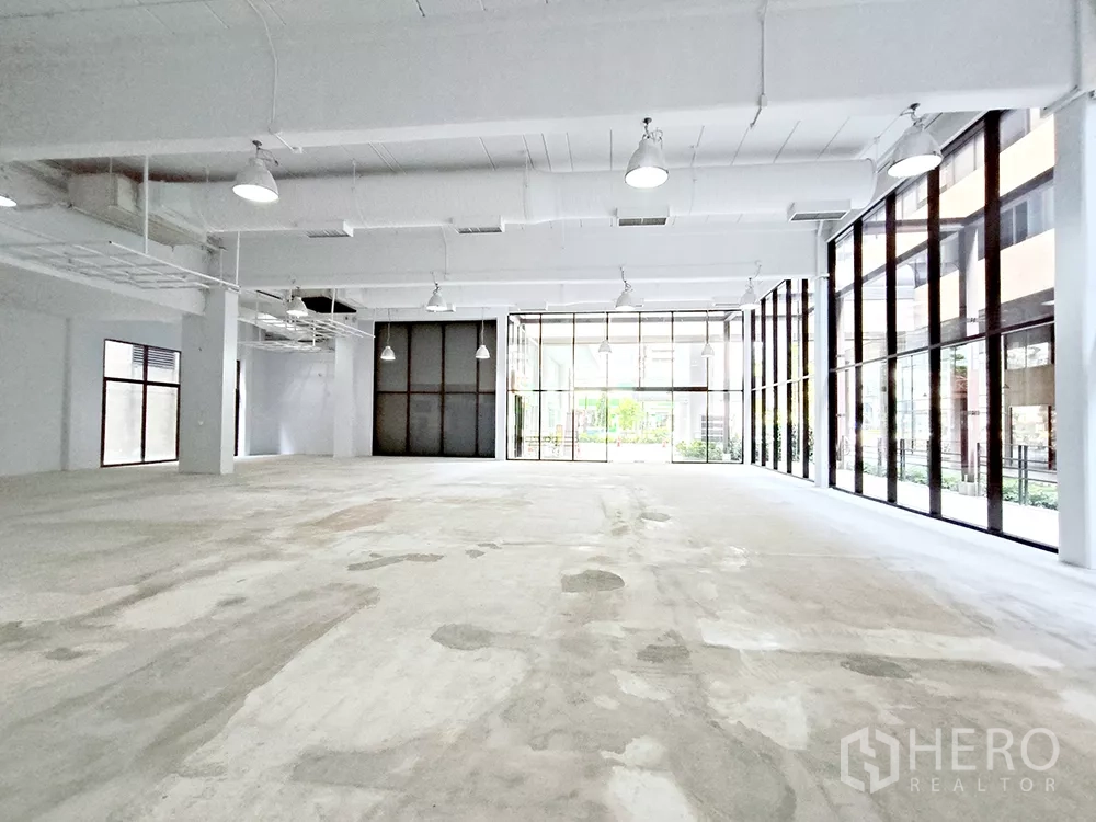 Office Space for rent in Watthana, Bangkok - Spacious bare-shell office interior with high ceilings, pendant lights, and full-height windows.