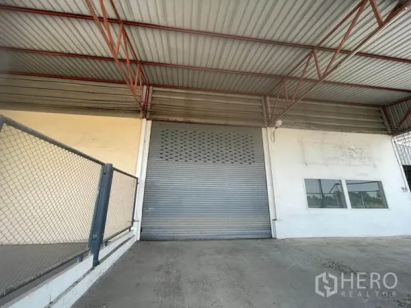 工厂 出租在Lat Lum Kaeo, Pathum Thani - 卷闸门与钢梁屋顶的近景，旁边为办公区窗户。