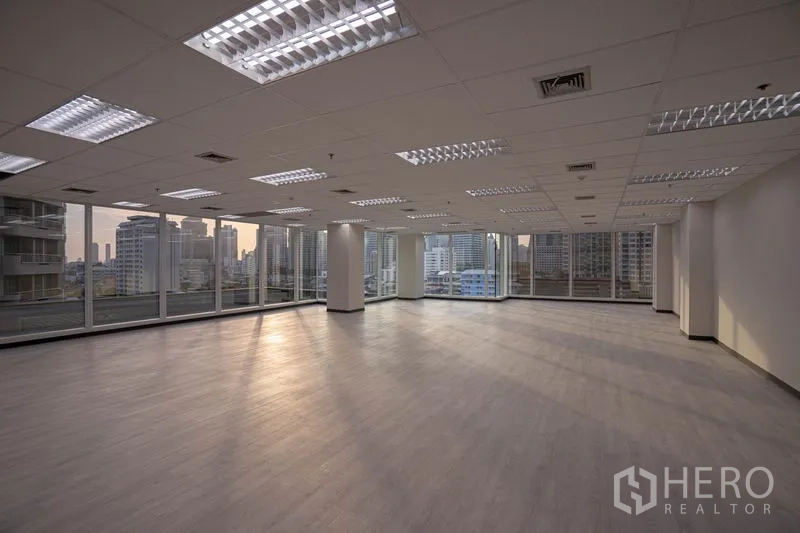 Office Space for rent in Sathon, Bangkok - Open-plan office floor with corner windows and city skyline views at sunset.