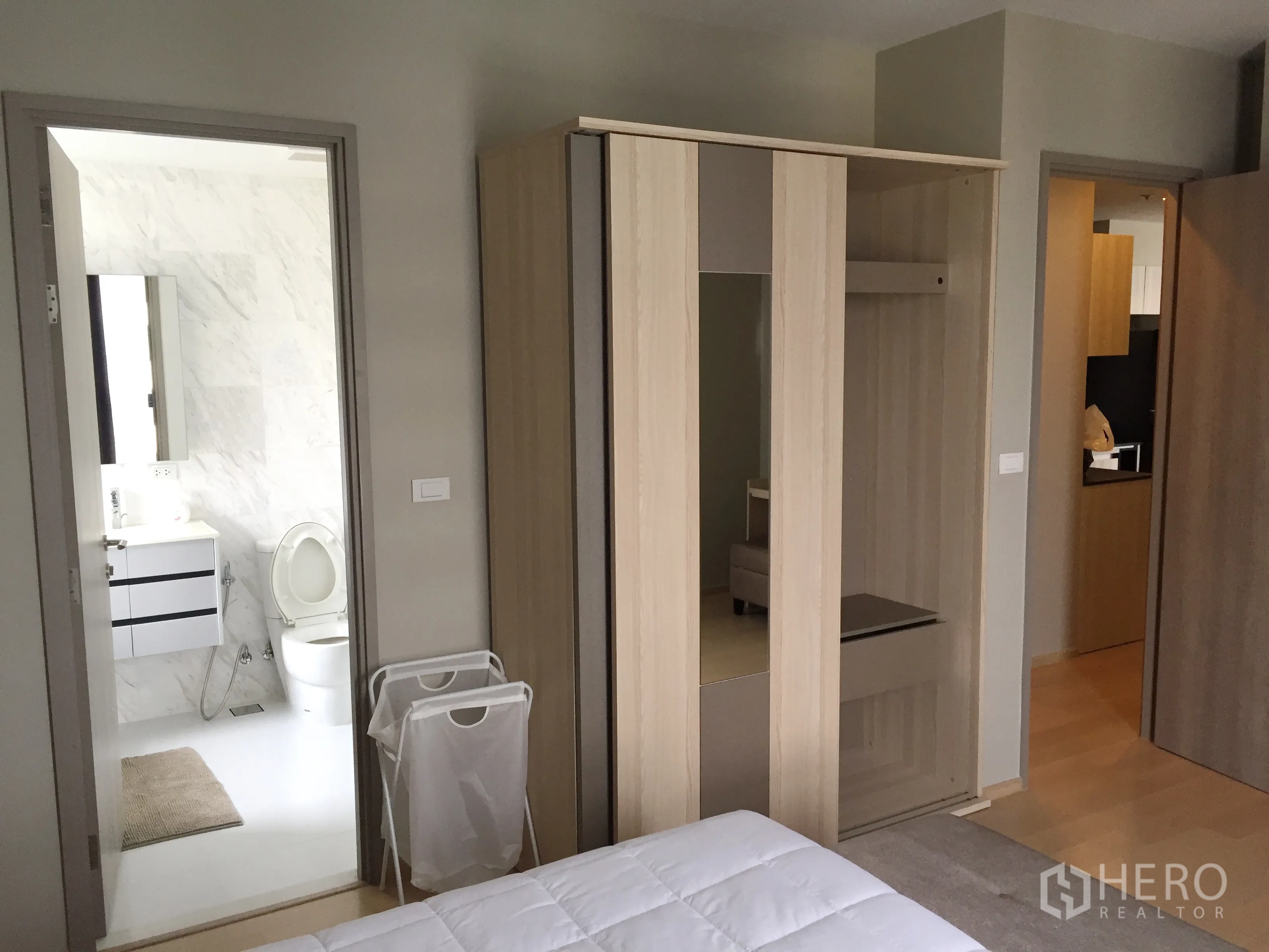 Condominium for rent in Watthana, Bangkok - Bedroom with built-in wardrobe and doorway to a marble-tiled bathroom.
