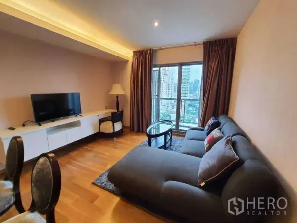 Condominium for sale in Watthana, Bangkok - Living area with sectional sofa, rug, coffee table and balcony city view.