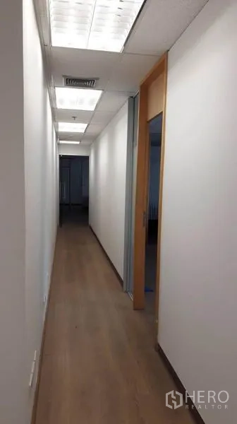 Office Space for rent in Bang Rak, Bangkok - Bright corridor with wooden floor, white walls, and fluorescent ceiling lights leading to private rooms.