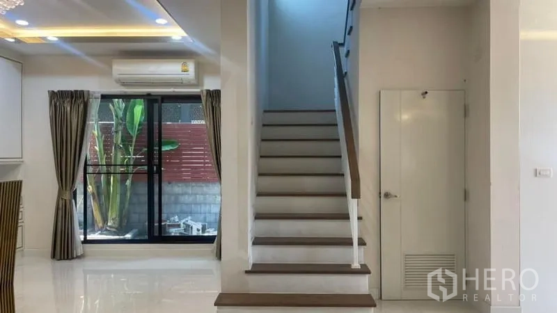 บ้าน ให้เช่าหรือขายในPrawet, Bangkok - บันไดมีพื้นที่เก็บของ ประตูกระจกเลื่อนไปยังสวนข้างบ้าน