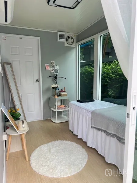 Detached House for sale in Bang Kapi, Bangkok - Interior of the garden room or studio with daybed, wide windows and light wood floors.