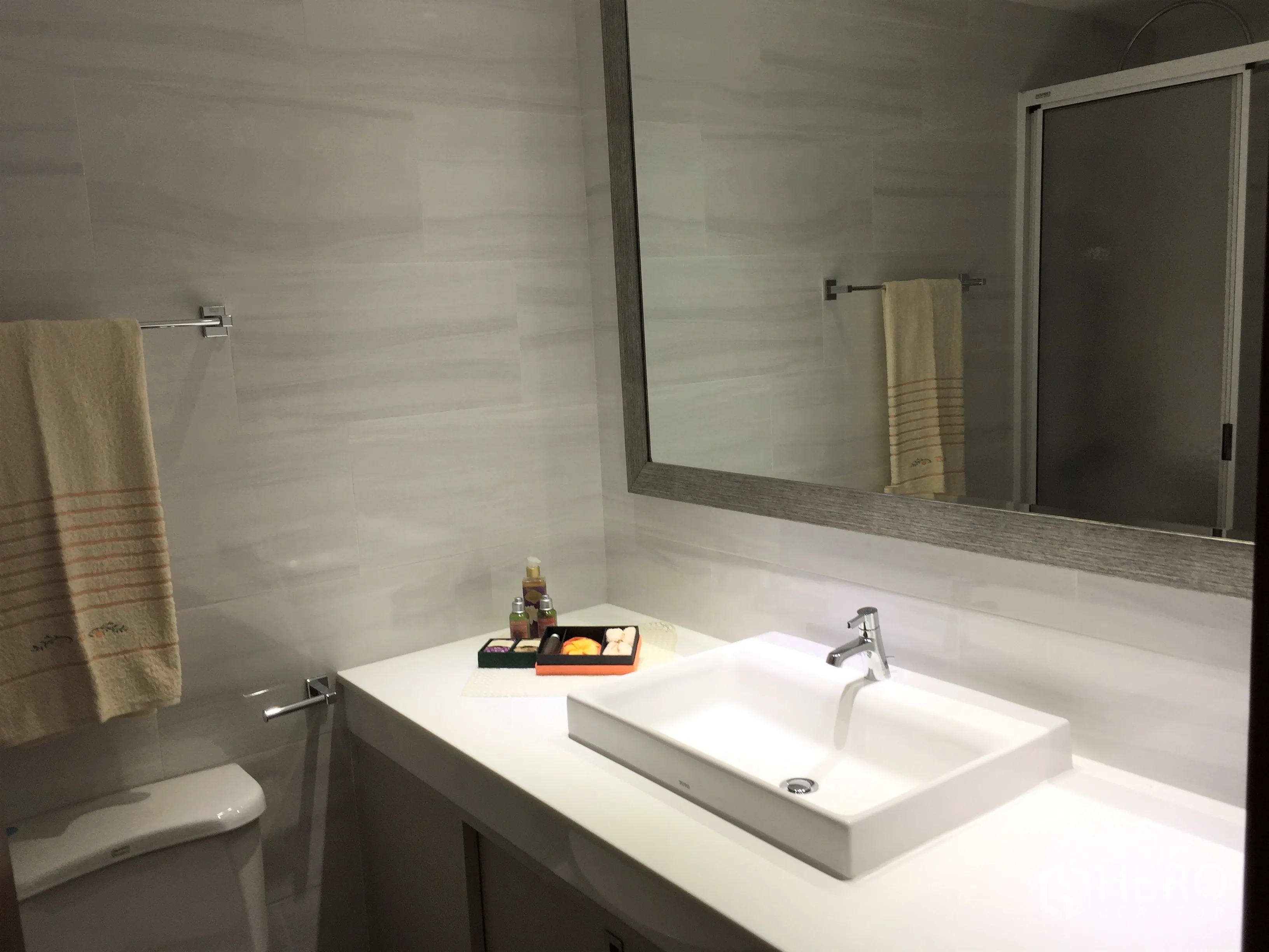 Condominium for rent in Watthana, Bangkok - Contemporary bathroom with wide countertop sink, large mirror and glass shower enclosure.