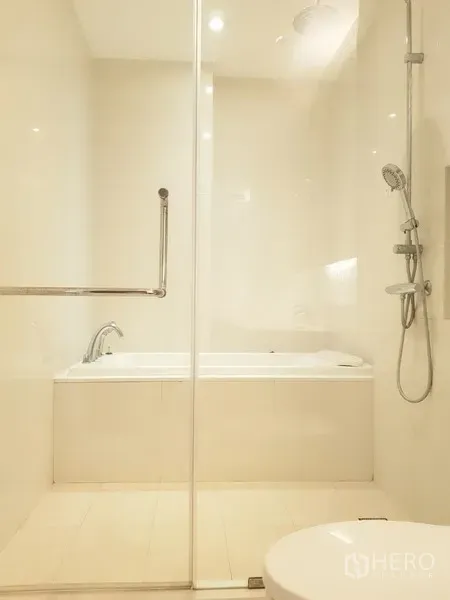 公寓 出租在Khlong Toei, Bangkok - 明亮卫生间，独立玻璃淋浴间与浴缸，配色柔和。