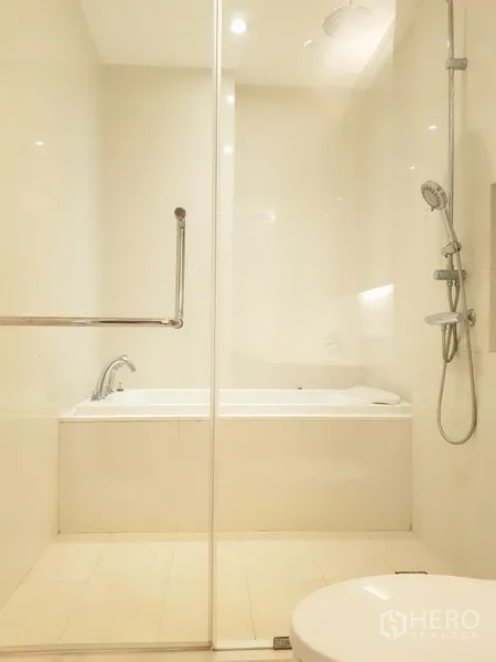 公寓 出租在Khlong Toei, Bangkok - 明亮卫生间，独立玻璃淋浴间与浴缸，配色柔和。