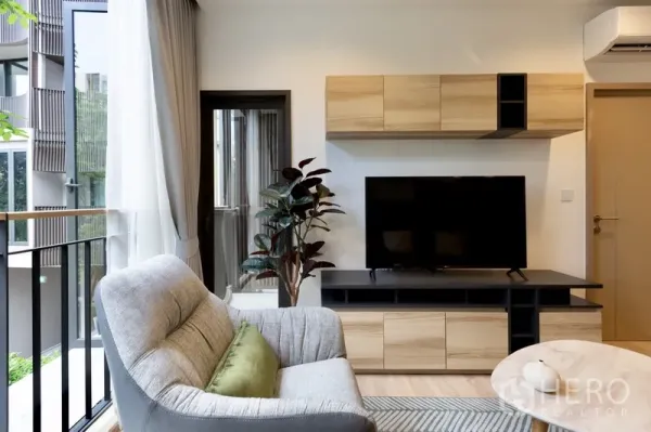 คอนโด ให้เช่าหรือขายในWatthana, Bangkok - ผนังทีวีตู้ไม้ในห้องนั่งเล่นและประตูกระจกเปิดสู่ระเบียง
