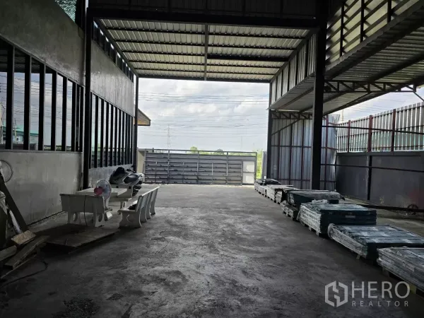 Warehouse for sale in Lat Lum Kaeo, Pathum Thani - Covered loading bay with wide sliding gate and drive-through truck access at the warehouse entrance.