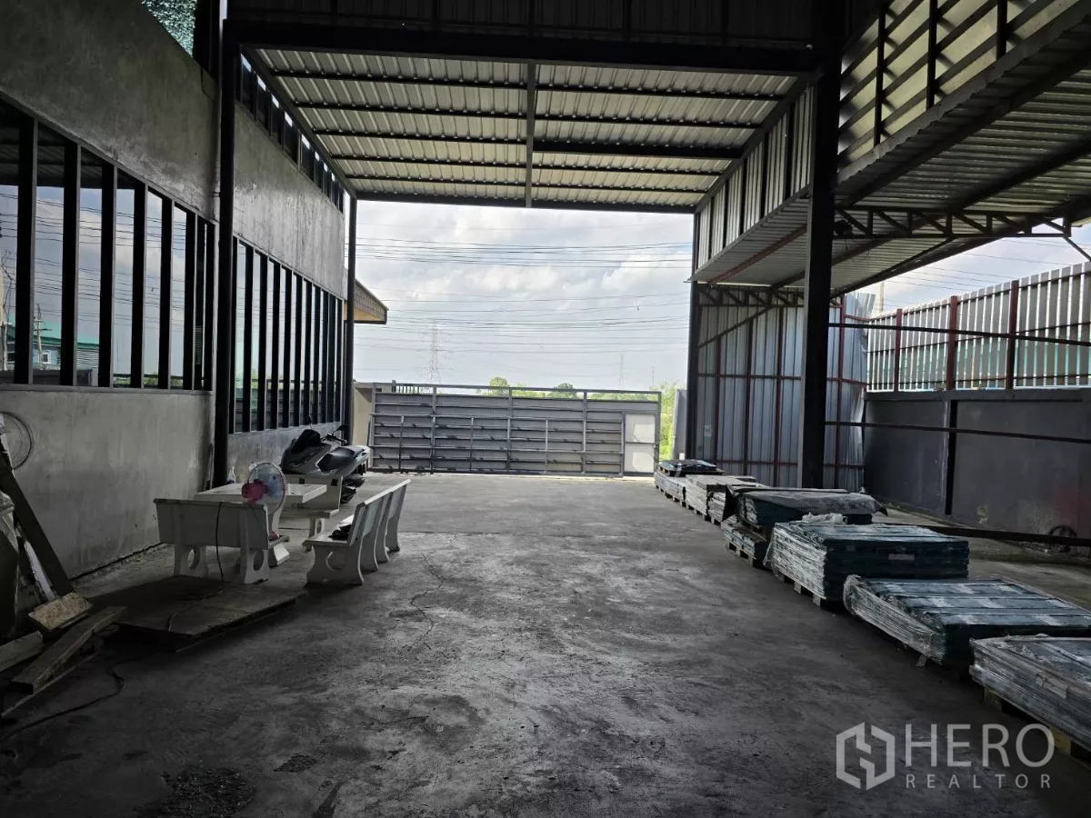 Warehouse for sale in Lat Lum Kaeo, Pathum Thani - Covered loading bay with wide sliding gate and drive-through truck access at the warehouse entrance.