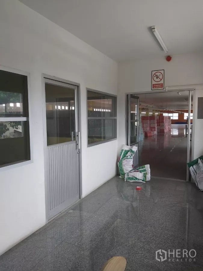 Warehouse for rent in Krathum Baen, Samut Sakhon - Internal corridor with doors and windows opening to a storage hall with bagged goods.