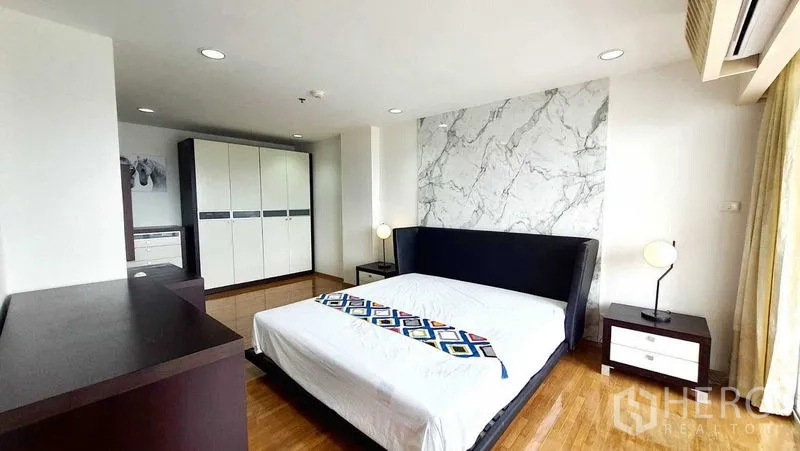 Condominium for sale in Bang Kho Laem, Bangkok - Primary bedroom with king bed, marble accent wall and spacious wardrobe.