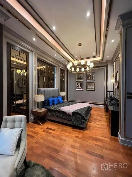 Detached House for rent or sale in Thawi Watthana, Bangkok - Stylish bedroom with wood floors, warm lighting and classic wall panels.