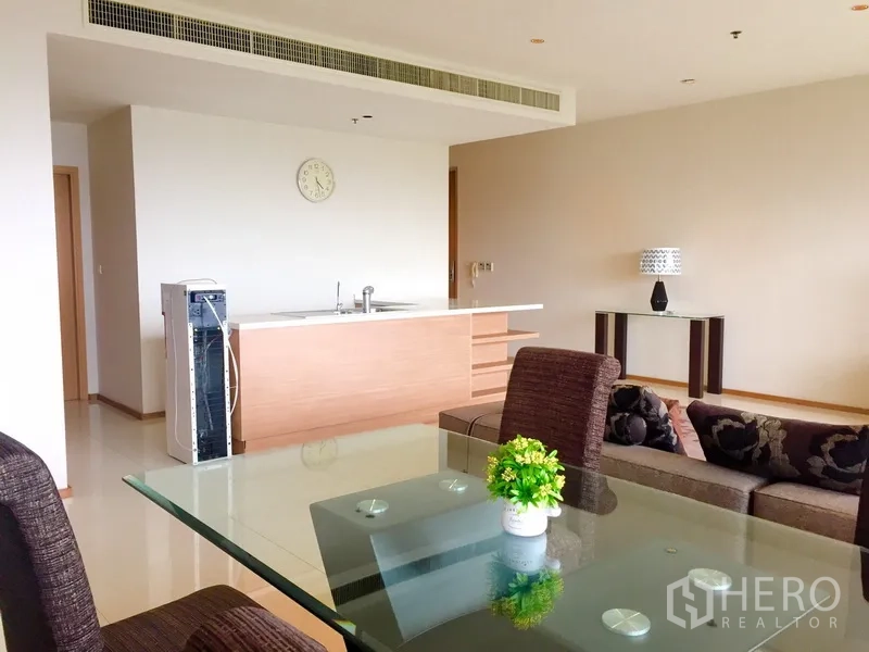 คอนโด ให้เช่าในKhlong Toei, Bangkok - พื้นที่นั่งเล่นแบบโอเพ่นแปลน โต๊ะอาหารกระจก เก้าอี้สีน้ำตาล โซฟา และไอส์แลนด์ครัวสไตล์มินิมอลพร้อมแอร์ฝังฝ้า