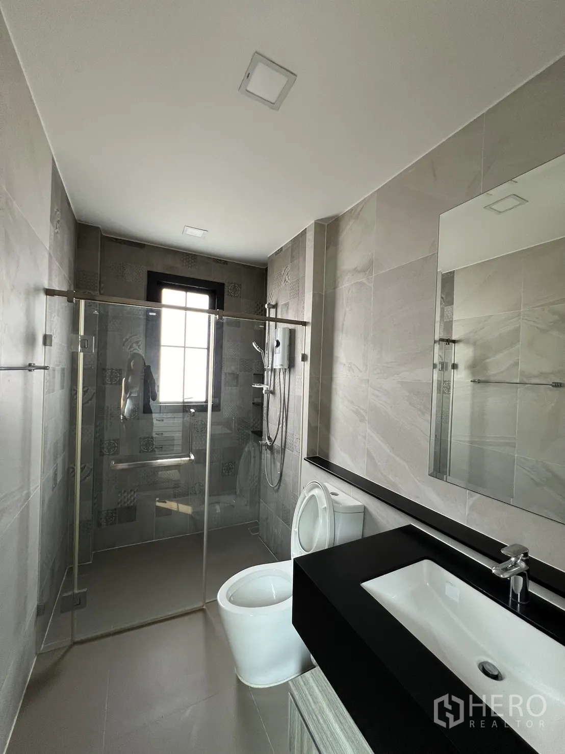 Detached House for rent or sale in Prawet, Bangkok - Ensuite bathroom with patterned tiles and glass-enclosed shower.