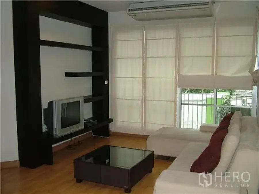 คอนโด ให้เช่าในKhlong Toei, Bangkok - ห้องนั่งเล่นมีโซฟาเข้ามุม ชั้นวางทีวีสีดำ และหน้าต่างบานใหญ่เปิดสู่ระเบียง