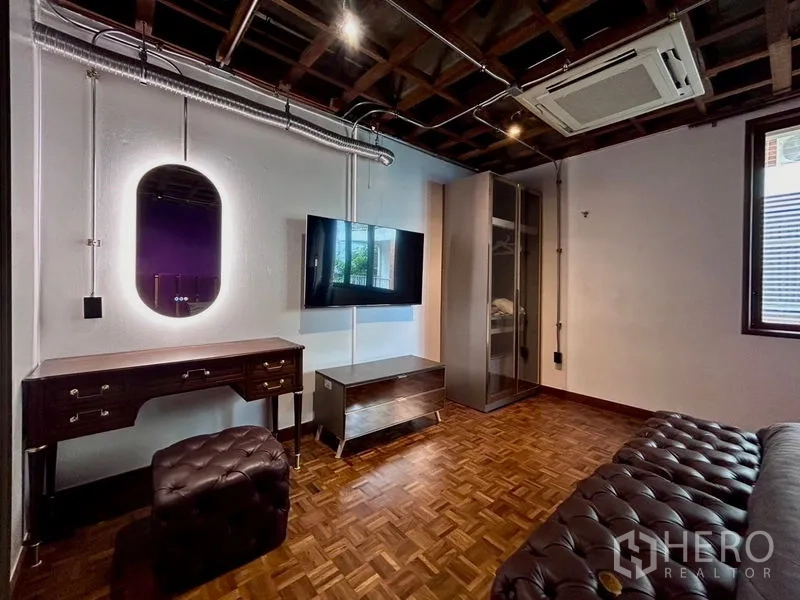 Apartment for rent in Khlong Toei, Bangkok - Multipurpose room with vanity desk, wall-mounted TV, leather bench and ceiling ducting over parquet flooring.