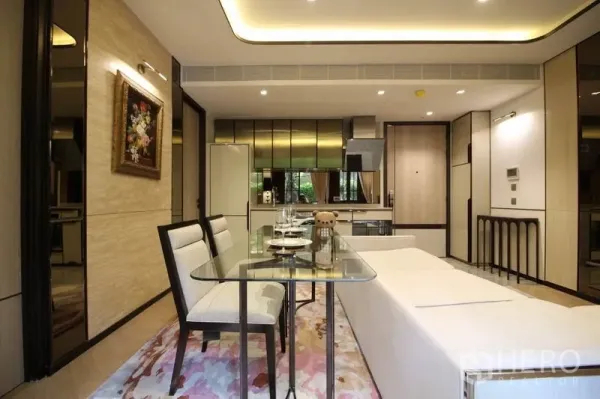 Condominium for rent in Watthana, Bangkok - Dining area looking toward a sleek kitchen with reflective cabinetry, fridge and in-unit washer.