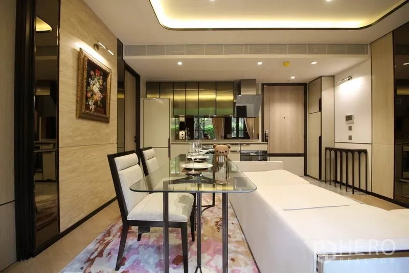 Condominium for rent in Watthana, Bangkok - Dining area looking toward a sleek kitchen with reflective cabinetry, fridge and in-unit washer.