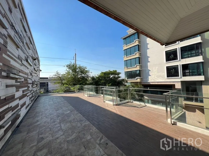 店屋 出租在Suan Luang, Bangkok - 上层露台设玻璃栏杆，位于现代建筑之间。