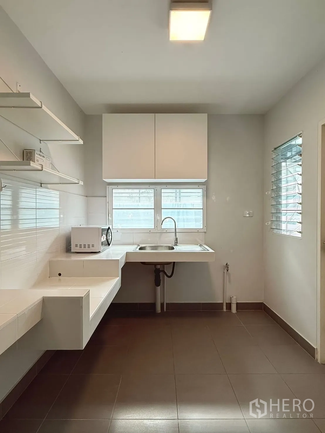 独栋房屋 for rent in Bang Phli, Samut Prakan - 简洁厨房，白色台面与水槽、墙面搁架及窗户。
