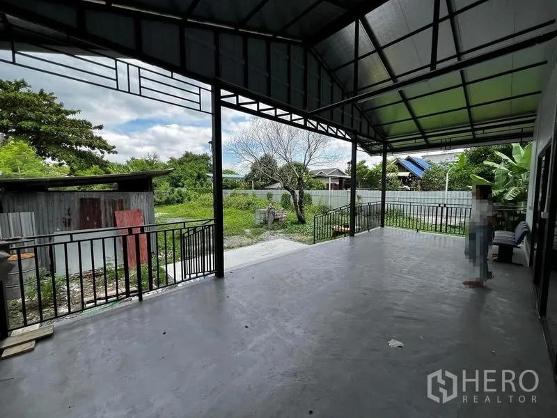 Warehouse for rent in Suan Luang, Bangkok - Large covered terrace used as a loading area overlooking a green yard with metal railings.