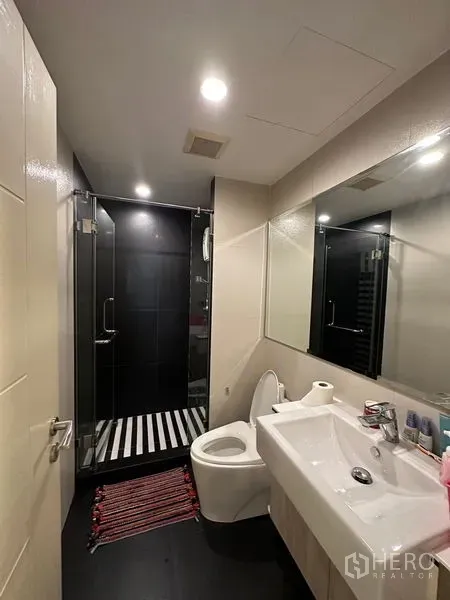 คอนโด ให้เช่าในKhlong Toei, Bangkok - ห้องน้ำสมัยใหม่ พร้อมฉากกั้นอาบน้ำกระจก ผนังโทนดำ อ่างล้างหน้า และโถสุขภัณฑ์