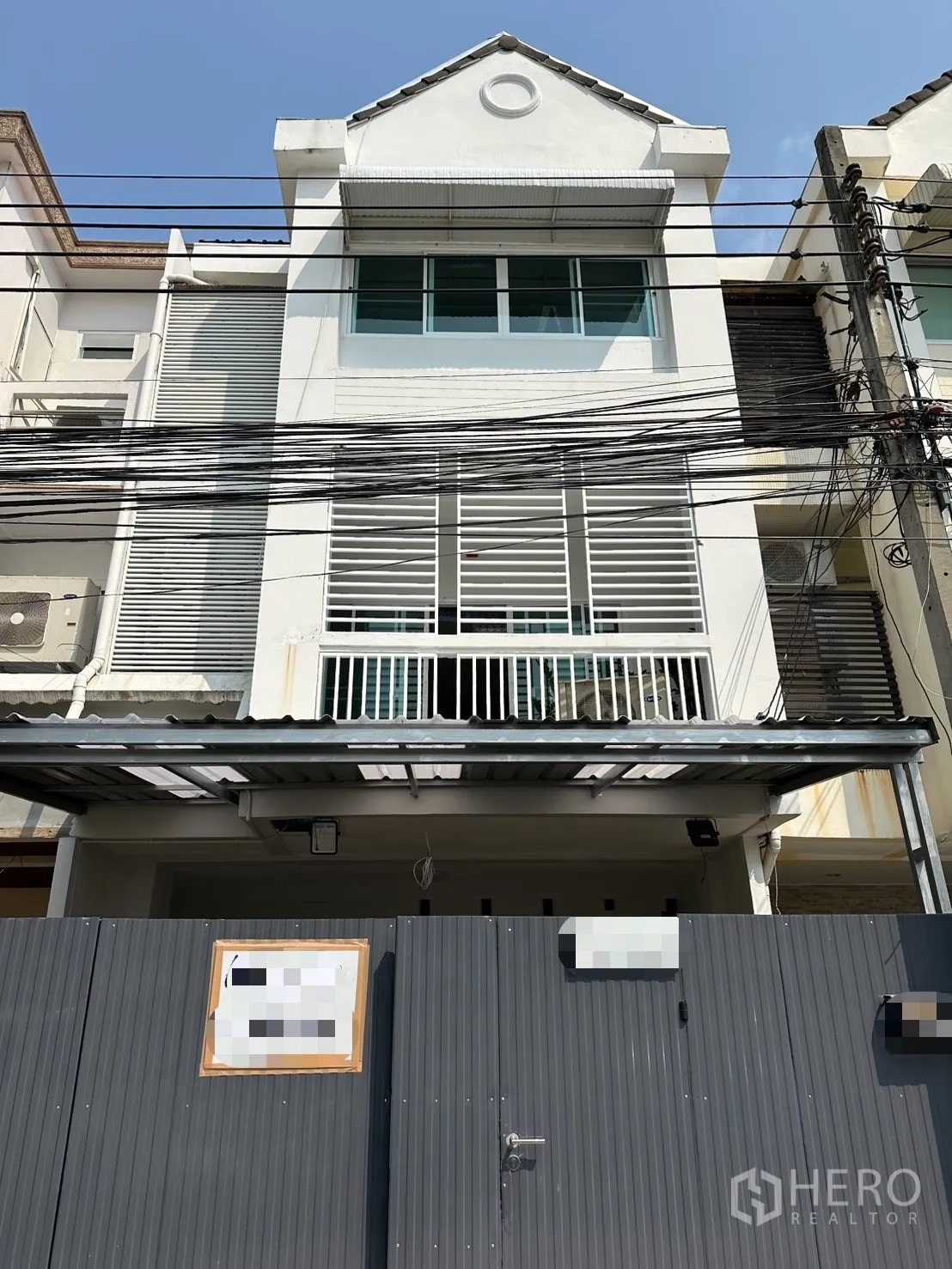 ทาวน์เฮาส์ for rent in Watthana, Bangkok - ทาวน์เฮ้าส์สีขาวสูงสามชั้น ด้านหน้ามีกำแพงรั้วและระแนงระเบียง