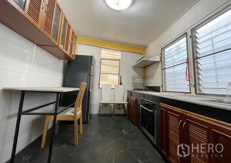 Detached House for rent in Khlong Toei, Bangkok - Separate Thai kitchen with cooktop, range hood, dark counters and louvered wooden cabinets.
