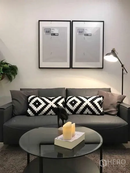 คอนโด ให้เช่าหรือขายในRatchathewi, Bangkok - ห้องนั่งเล่นพร้อมโต๊ะกลางกระจกทรงกลม หมอนลายเรขาคณิต และกรอบรูปมินิมอลสองชิ้น