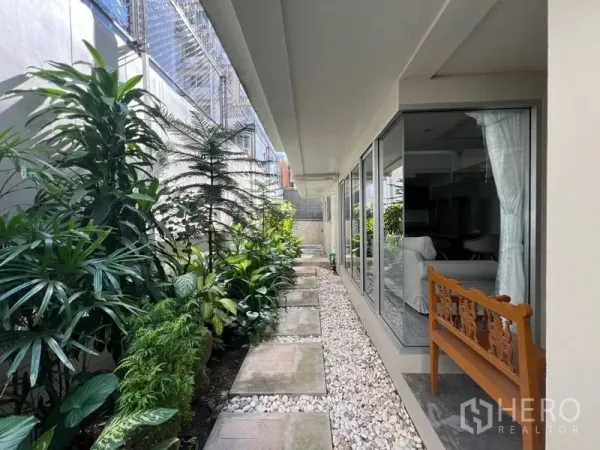 ทาวน์เฮาส์ ให้เช่าในKhlong Toei, Bangkok - ทางเดินข้างบ้านมีสวนไม้ใบ เข้าถึงตัวบ้านผ่านผนังกระจกสูงจรดเพดาน