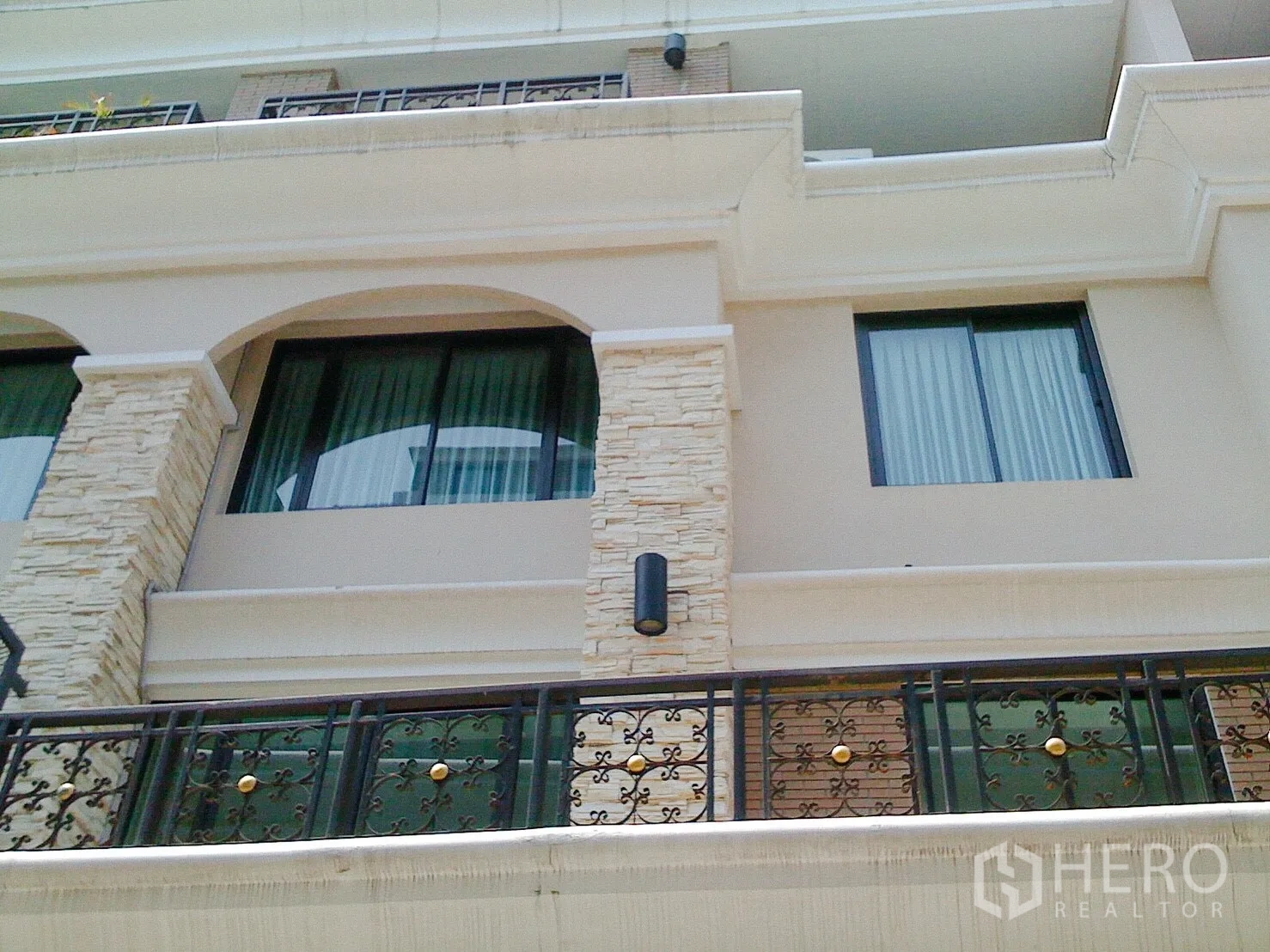 ทาวน์เฮาส์ ให้เช่าในKhlong Toei, Bangkok - ด้านหน้าทาวน์เฮ้าส์หลายชั้นตกแต่งหิน ผนังโค้ง และระเบียงเหล็กดัดในกรุงเทพฯ