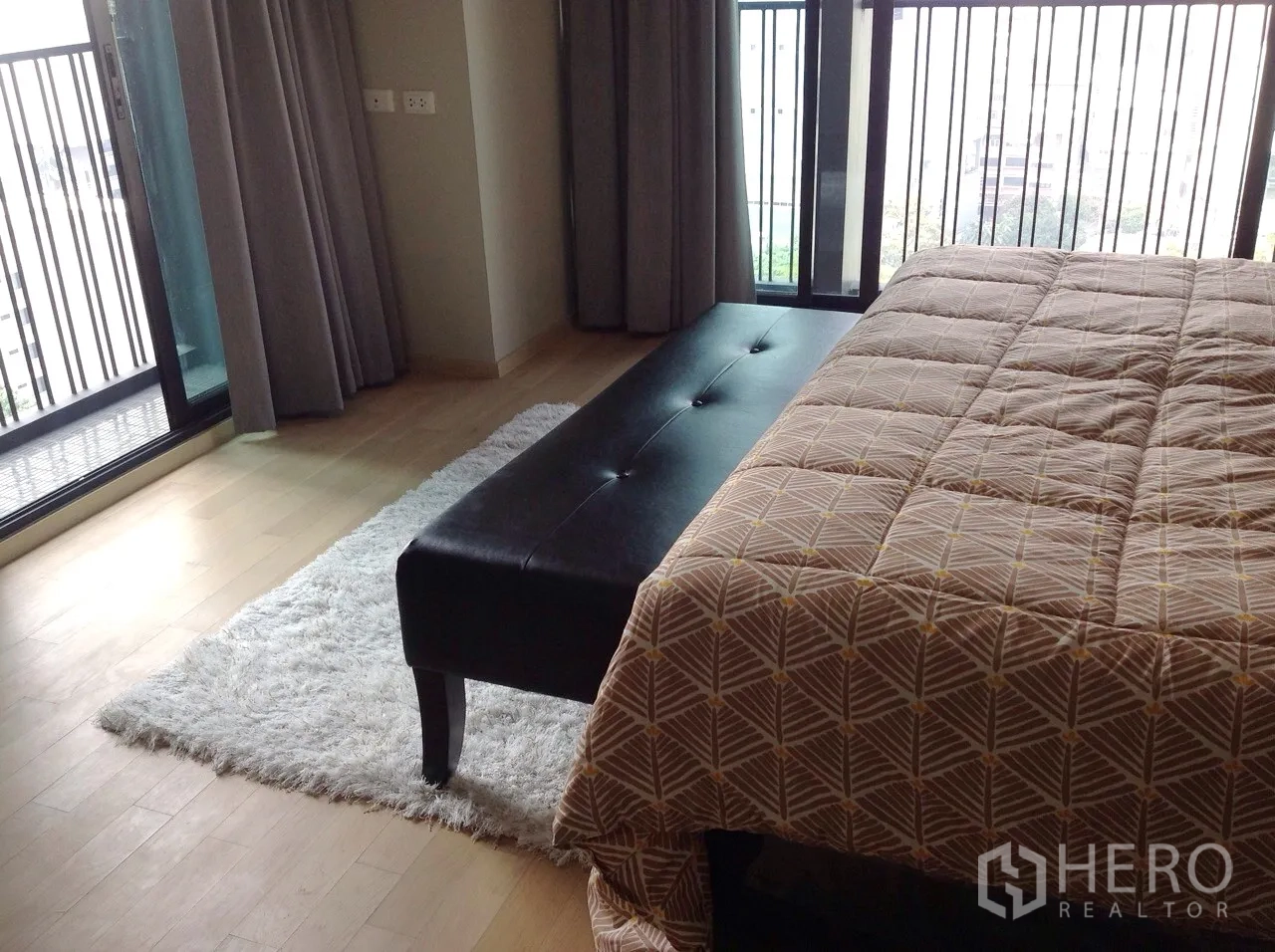 Condominium for rent or sale in Watthana, Bangkok - Bedroom corner with a bench, shag rug and floor-to-ceiling balcony doors.