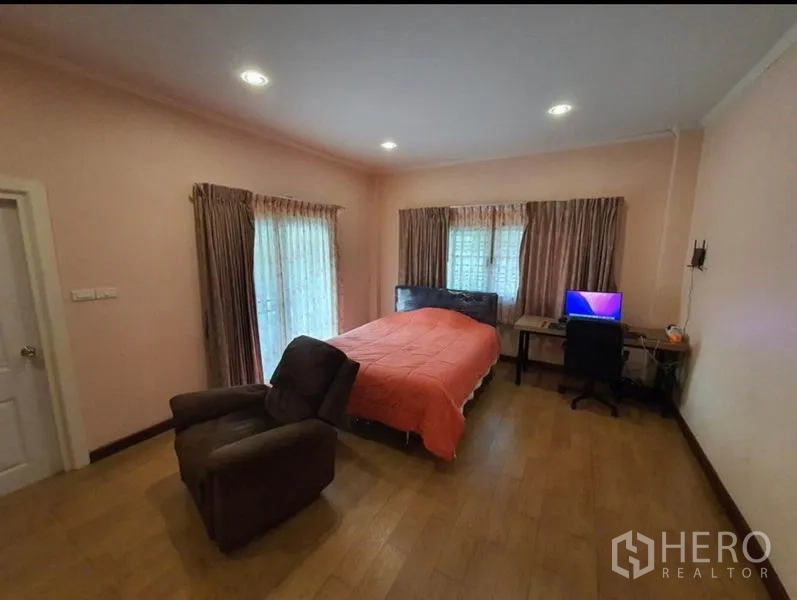 独立式住宅 出售在Sai Mai, Bangkok - 一层卧室，粉色墙面、转角窗、书桌与躺椅。