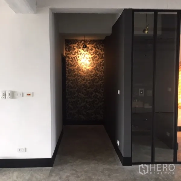 คอนโด ให้เช่าในWatthana, Bangkok - โถงทางเดินแคบ ผนังลายกราฟิกพร้อมไฟแขวนอุ่น อยู่ข้างฉากกั้นกระจกสีเข้ม.