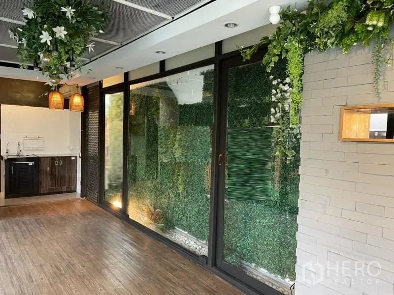 零售空间 出租在Watthana, Bangkok - 店内带落地窗、绿植墙、木地板和服务台，配有吊灯。